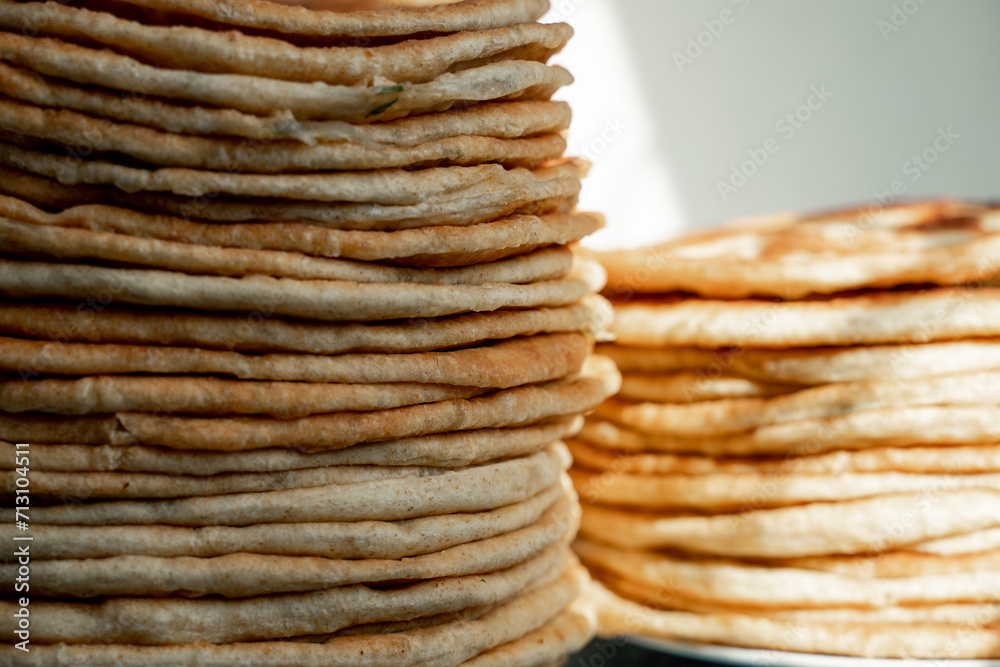 Flatbread lavash, chapati, naan, heap of tortilla on a blue background Homemade flatbread stacked. Flatbread lavash, chapati, naan, heap of tortilla on a blue background Homemade flatbread stacked.