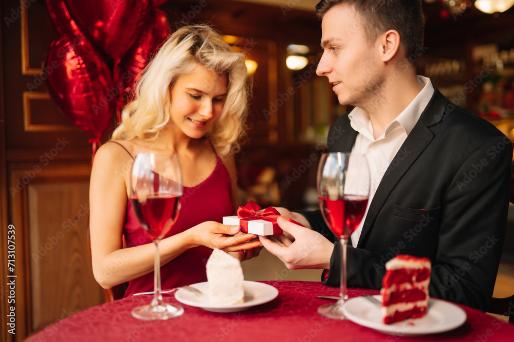 Beautiful young couple celebrating Valentine's Day in the restaurant. Exchange of gifts. Romantic day together. Beautiful young couple celebrating Valentine's Day in the restaurant. Exchange of gifts. Romantic day together.