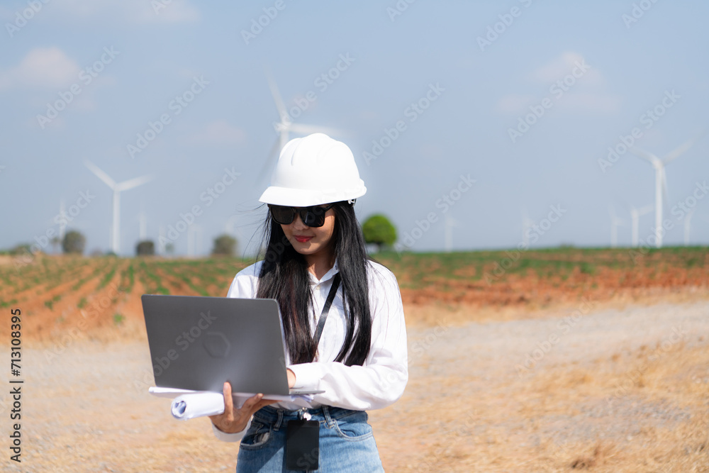 Portrait of a beautiful asian woman engineer working with laptop in wind turbine field