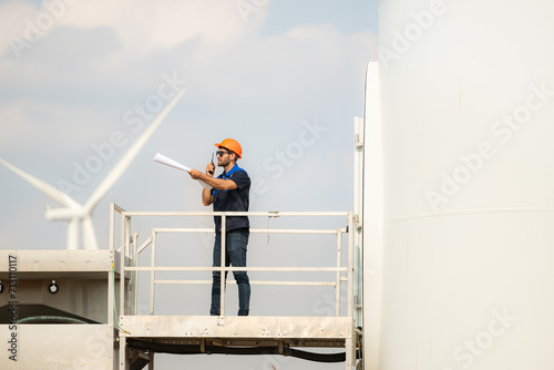 Technician checking wind turbine in wind turbine farm for maintenance. © Wosunan