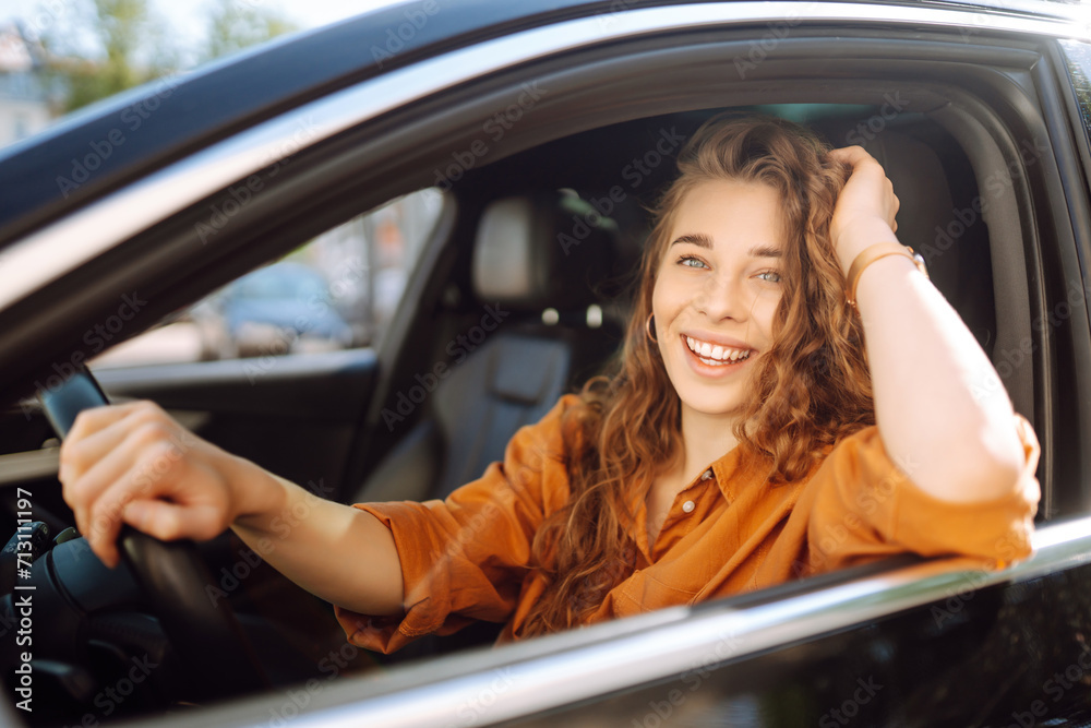 A happy woman is driving a car and smiling. Automobile travel. Sharing a car. Lifestyle concept.