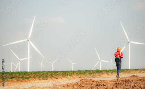 Engineer working in wind turbine farm with blue sky background