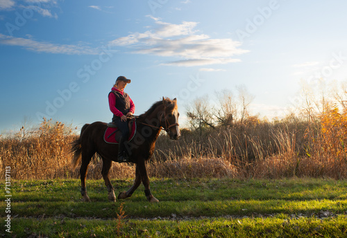 Young girl riding a horse in autumn.