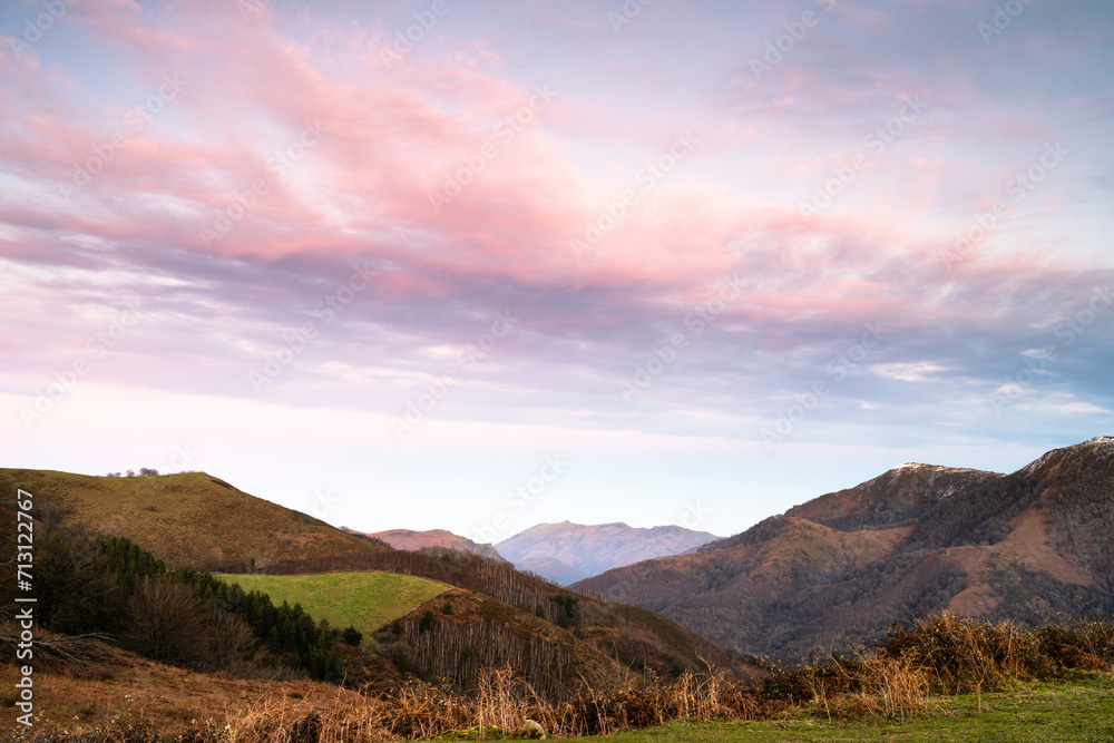 Landscape of the Basque Country with mountains and the Rhune mountain in the background. Golden hour and pink clouds. Spain.