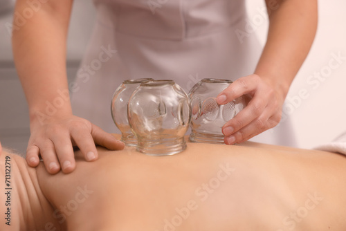 Therapist giving cupping treatment to patient indoors, closeup