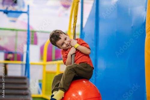 A cheerful little boy is playing in the children's entertainment center on the playground.