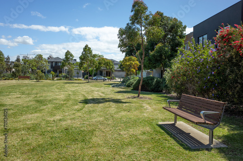 Background texture of a public suburban park with vacant grass lawn, sitting bench seats and Australian native plants in a residential neighbourhood. Williams Landing, Melbourne VIC Australia.