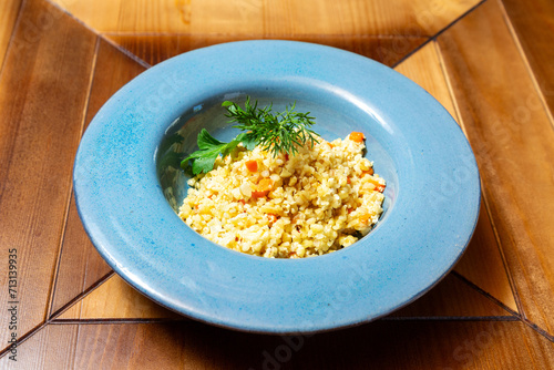 Bulgur porridge with parsley. On a wooden table.