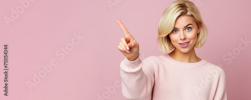 Young woman smiling and pointing fingerto empty copy space standing isolated on pink background,