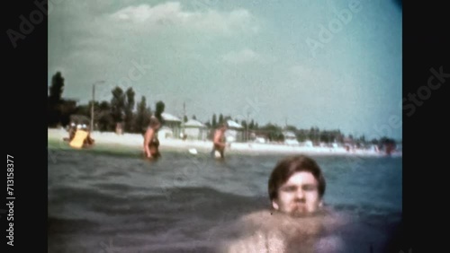 People swim in sea water in summer beach resort. Woman, young man swimming in ocean on sunny vacation. Happy holiday. Fun activity in water. Home movies. Lifestyle archive. Vintage color film 1980s