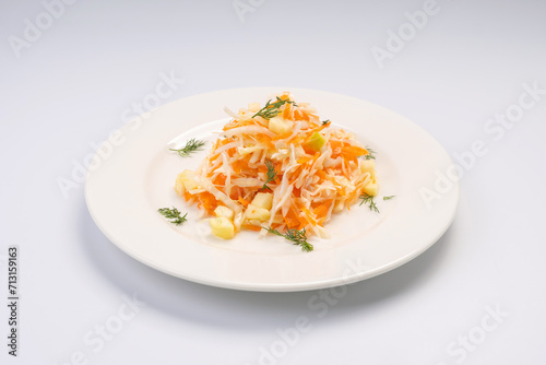 Dinner. Cabbage and apple salad with carrots on a white plate and a white background