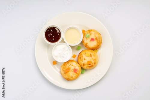 Breakfast. Cheesecakes with sauces and dried fruits on a white plate and a white background.