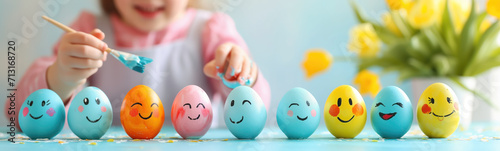 Happy child painting eggs by brush indoors. Easter concept.