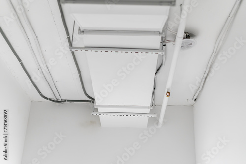 This image shows a large industrial air ventilation unit mounted on a white wall, with venting slats directing airflow within a contemporary building.