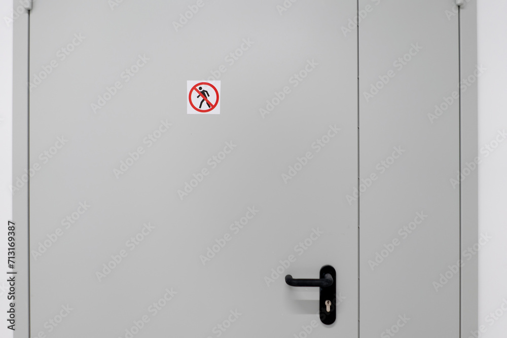This image shows a closed white door in a contemporary building with a clear no entry sign affixed near its handle, indicating restricted access. This image shows a closed white door in a contemporary building with a clear no entry sign affixed near its handle, indicating restricted access.