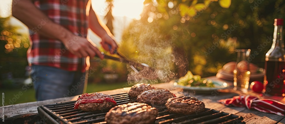 a man puts burger buns on the grill of a gas grill A gas grill is installed in the backyard of the household interesting pastime with family and friends. Copy space image. Place for adding text - obrazy, fototapety, plakaty 