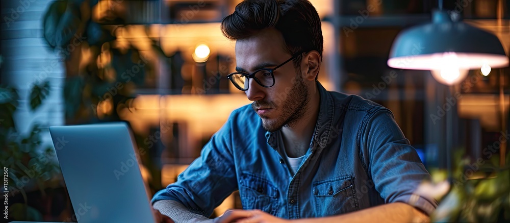 Professional sitting in office in front of laptop Developer thinking on solutions for work Home based student getting distant education Young serious bearded man in blue shirt working on deskto Professional sitting in office in front of laptop Developer thinking on solutions for work Home based student getting distant education Young serious bearded man in blue shirt working on deskto