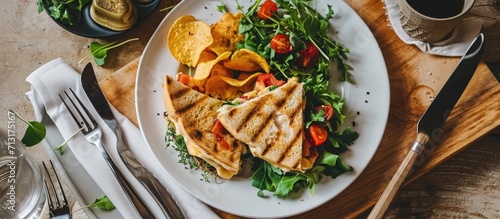 Top view of a tuna panini sandwitch in a white plate with crisps and salad Knife and Fork wrapped in a tissue on the side. Copy space image. Place for adding text