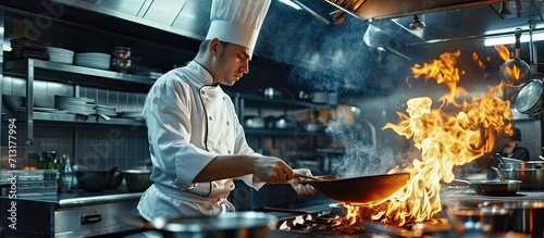 Chef cook food with fire at kitchen restaurant Cook with wok at kitchen Chef male in uniform hold wok with fire. Copy space image. Place for adding text