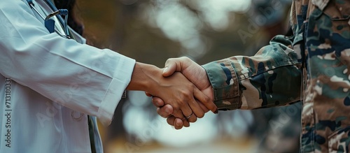 Happy military man shaking hands with female doctor while being with his wife at medical counselling. Copy space image. Place for adding text photo