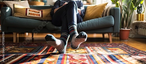 Young man standing by the sofa in the living room and putting elastic stretchable medical anti thrombosis or anti varicose sleeve socks or compression stockings on his tired legs. Copy space image photo