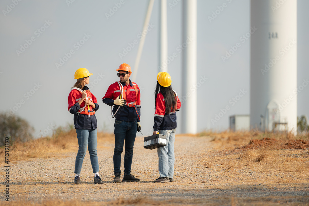 Team of engineers working on wind turbines in a wind farm Team of engineers working on wind turbines in a wind farm
