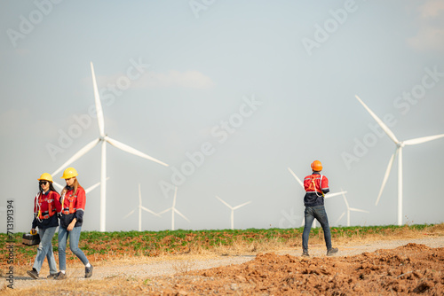 Engineer and technician greet each other in wind turbine farm with blue sky background