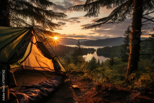 As the sun sets behind the forest, a tent perched atop a grassy hill gazes out at the tranquil lake, its tarpaulin glimmering in the fading light