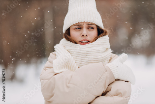 Young woman dressed coat scarf hat and mittens and winter weather at snowy winter park