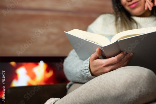 Close-up of woman reading a book in the warmth of her home.