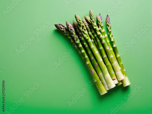 Fresh asparagus arranged in a heap on a green background  captured in a top-down view. Presented in a flat lay style  highlighting its health benefits.