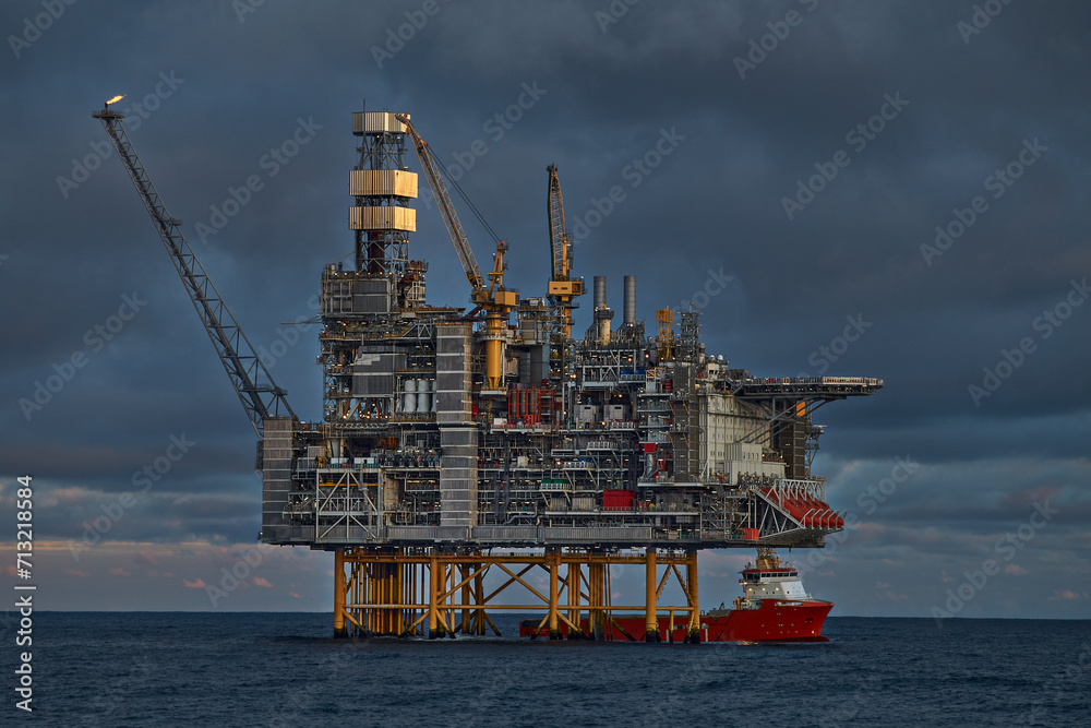 Supply vessel doing cargo operations with jack up drilling rig, offshore platform in the North sea.