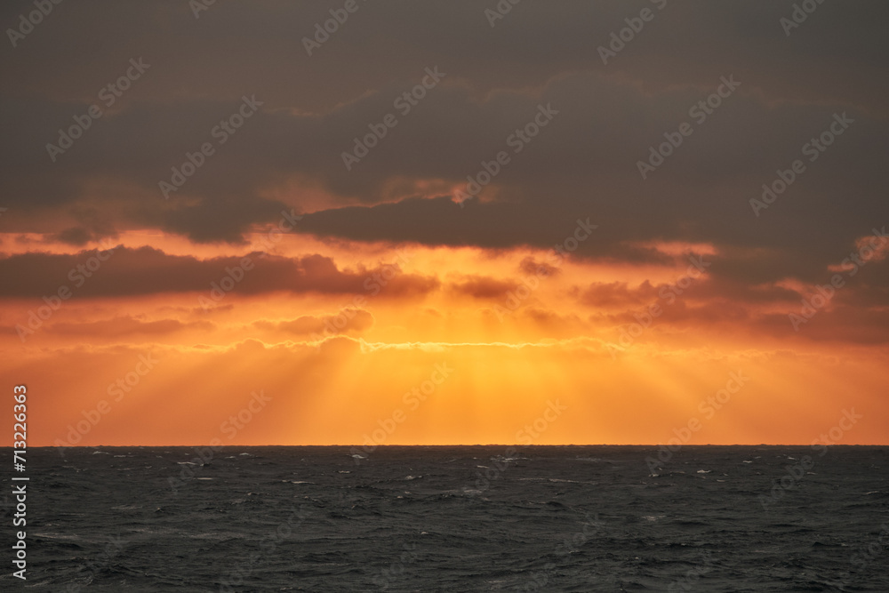 Beautiful orange sunset in the sea with sun rays shining through the clouds Beautiful orange sunset in the sea with sun rays shining through the clouds