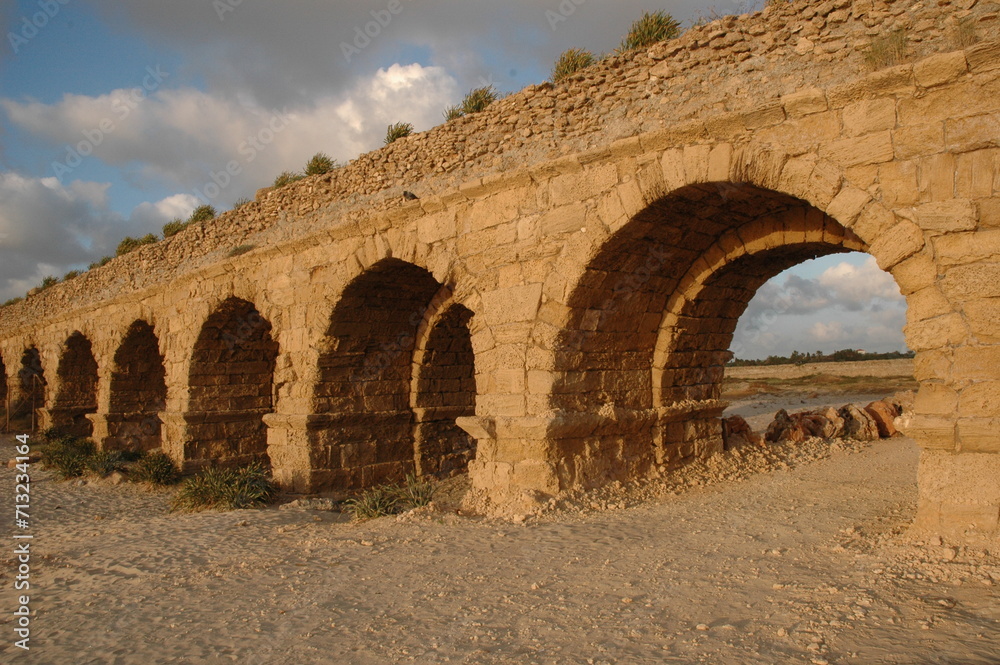Golden sunlight strikes the stones of the Hadrianic aqueduct of Caesarea Maritima along Israel's Mediterranean coast.