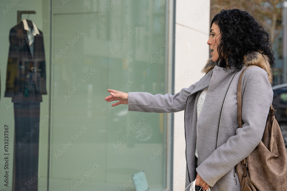 Woman shopping in the mall pointing new clothes at the window, showing a good discount price offer.