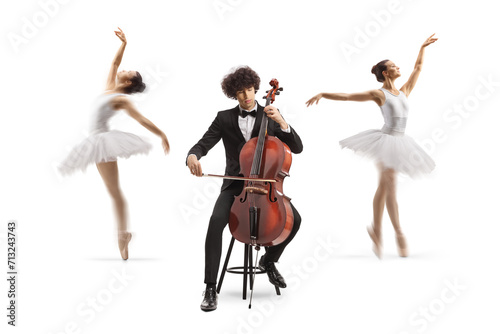 Male cellist sitting on a chair and performing and ballerinas dancing in the back