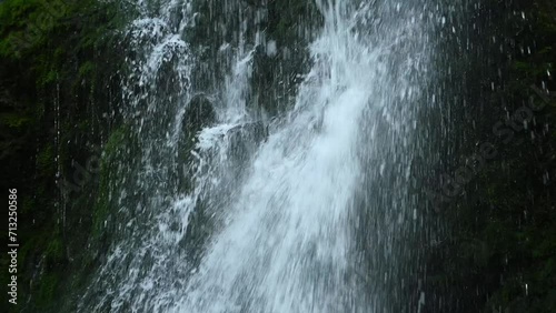 Water falls on and sprinles from mossy stones from a waterfall (slow motion) photo