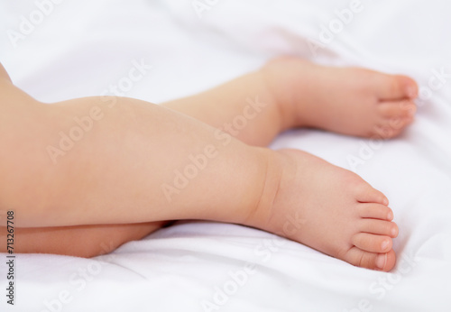 Feet  baby and legs of kid on bed for sleep  calm break and relax in nursery room at home. Closeup  foot and toes of tired young child asleep for newborn development  healthy childhood growth or rest