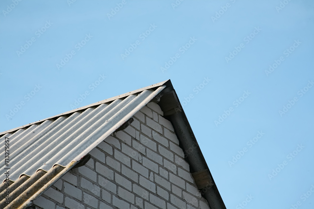 Top of a brick house roof against a blue sky
