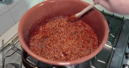 Bolognese sauce cooks in a terracotta saucepan photo