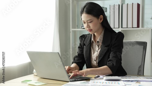 Young Asian business woman doing statistics planning and holding a chart, graph tablet and staff taking notes. Financial statistics success concept, 4k video