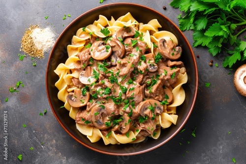 Beef Stroganoff made of beef fillet strips, sliced mushrooms, wide egg noodles, flour, beef broth, tomato paste, sour cream, Dijon mustard, Fresh parsley for garnish, top down view, clean background