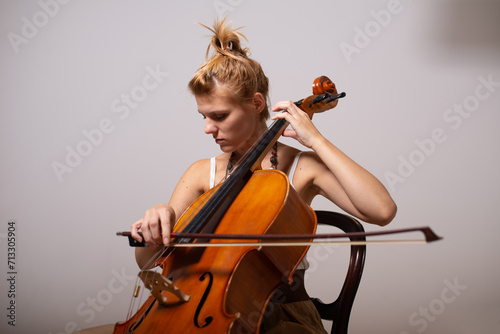 A young woman playing cello on the concert at night.