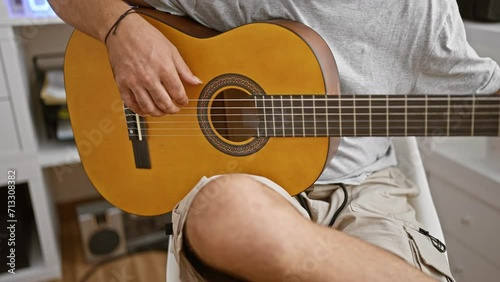 Close-up of a seated man strumming an acoustic guitar indoors, showcasing musical talent and leisure activity.