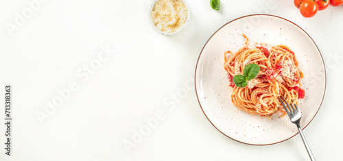 Spaghetti with tomato sauce, parmesan and basil on a light background, classic italian cuisine dish. Long banner format, top view