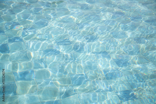 blue water surface background of swimming pool with tiles in sun light photo