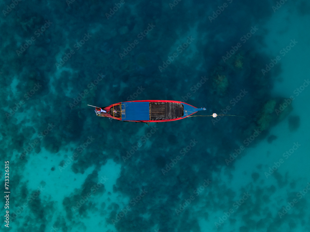 View from above, stunning aerial view of a long tail boat floating on a turquoise water. Phuket, Thailand.