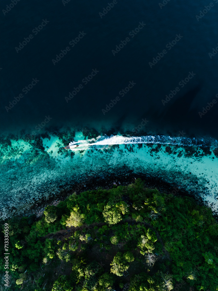 View from above, stunning aerial view of a longtail boat sailing on a turquoise water. Phuket, Thailand.