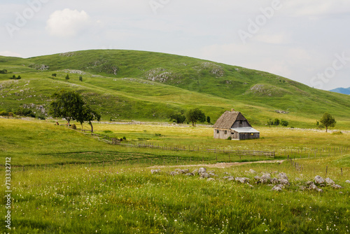 Rural house in a picturesque landscape, surrounded by rolling green hills.