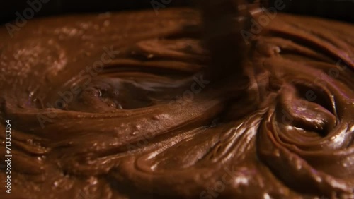 Close-up chocolatier mixing melted liquid chocolate with steel whisk. Hot chocolate mix and swirl in bowl. photo